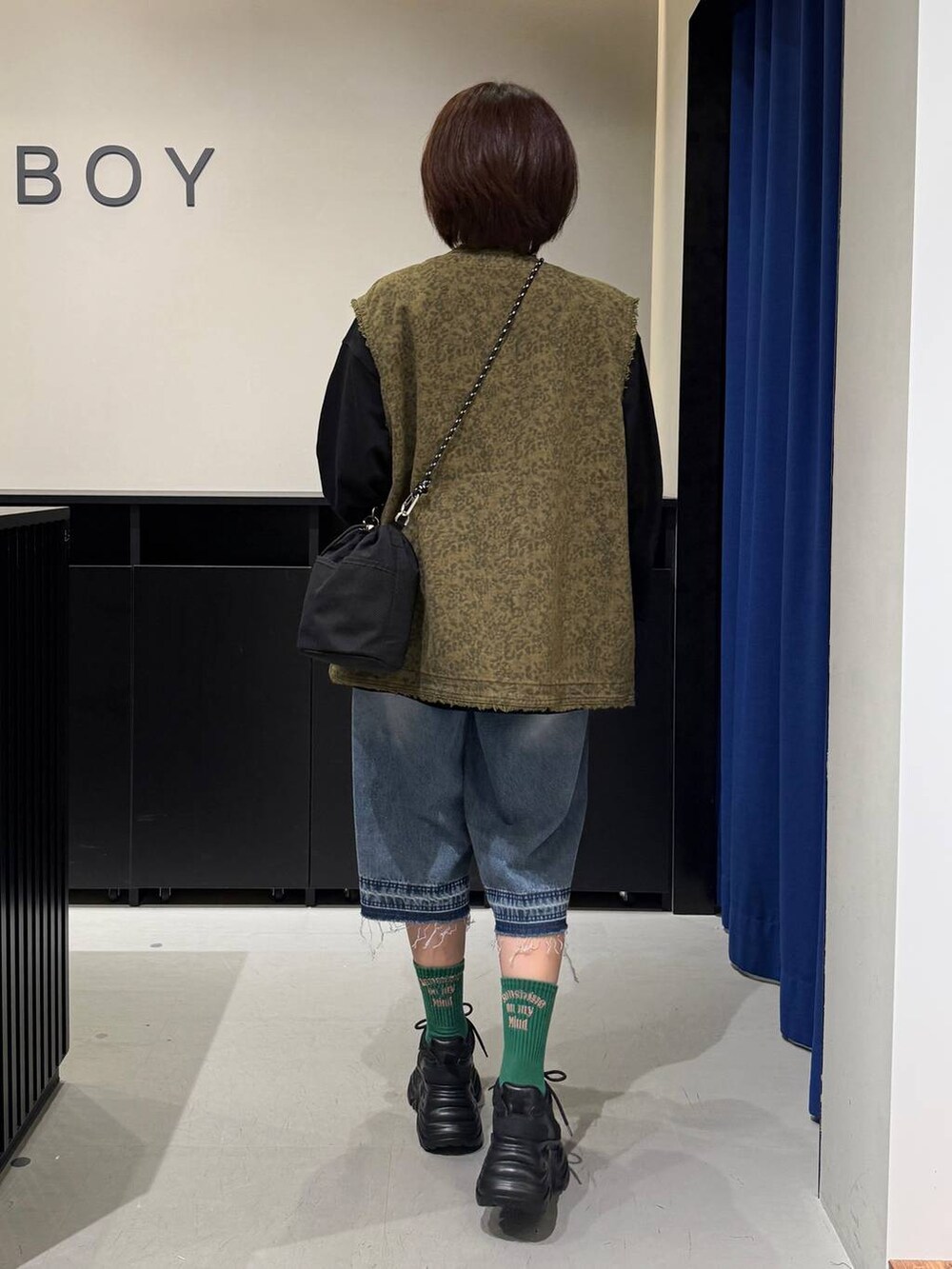 ブラック系のスニーカー、ブラック系のショルダーバッグ、ブルー系のデニムパンツを着用したレディースの夏コーディネートの5枚目の写真