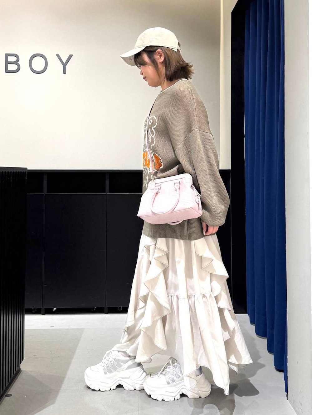 ホワイト系のスニーカー、ベージュ系のスカート、ピンク系のハンドバッグを着用したレディースの冬コーディネートの6枚目の写真
