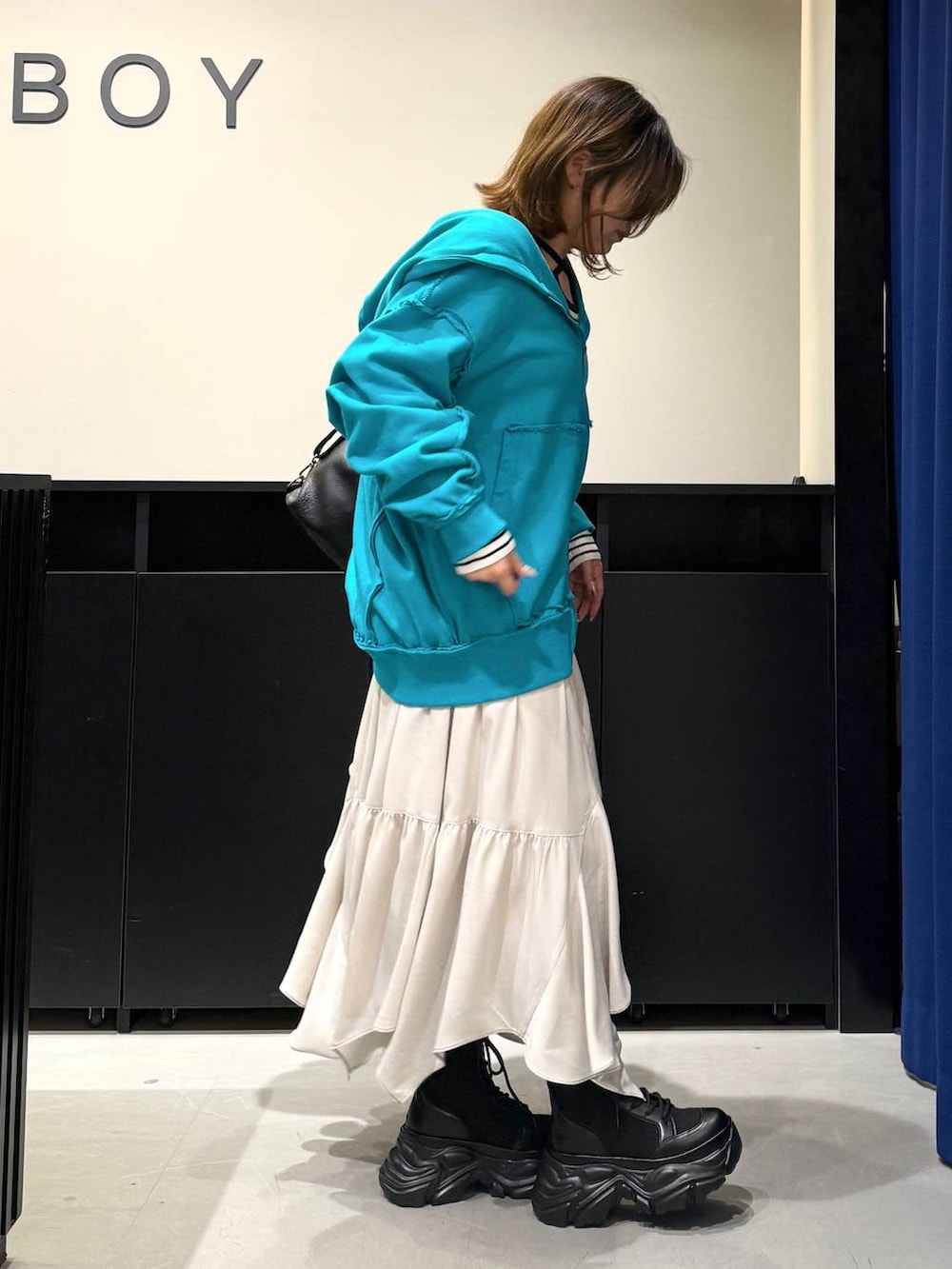 ブラック系のブーツ、ベージュ系のスカート、ホワイト系のニット/セーターを着用したレディースの冬コーディネートの3枚目の写真