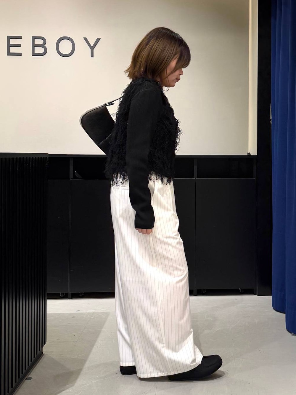 ブラック系のハンドバッグ、ブラック系のニット/セーター、ホワイト系のスラックスを着用したレディースの冬コーディネートの4枚目の写真