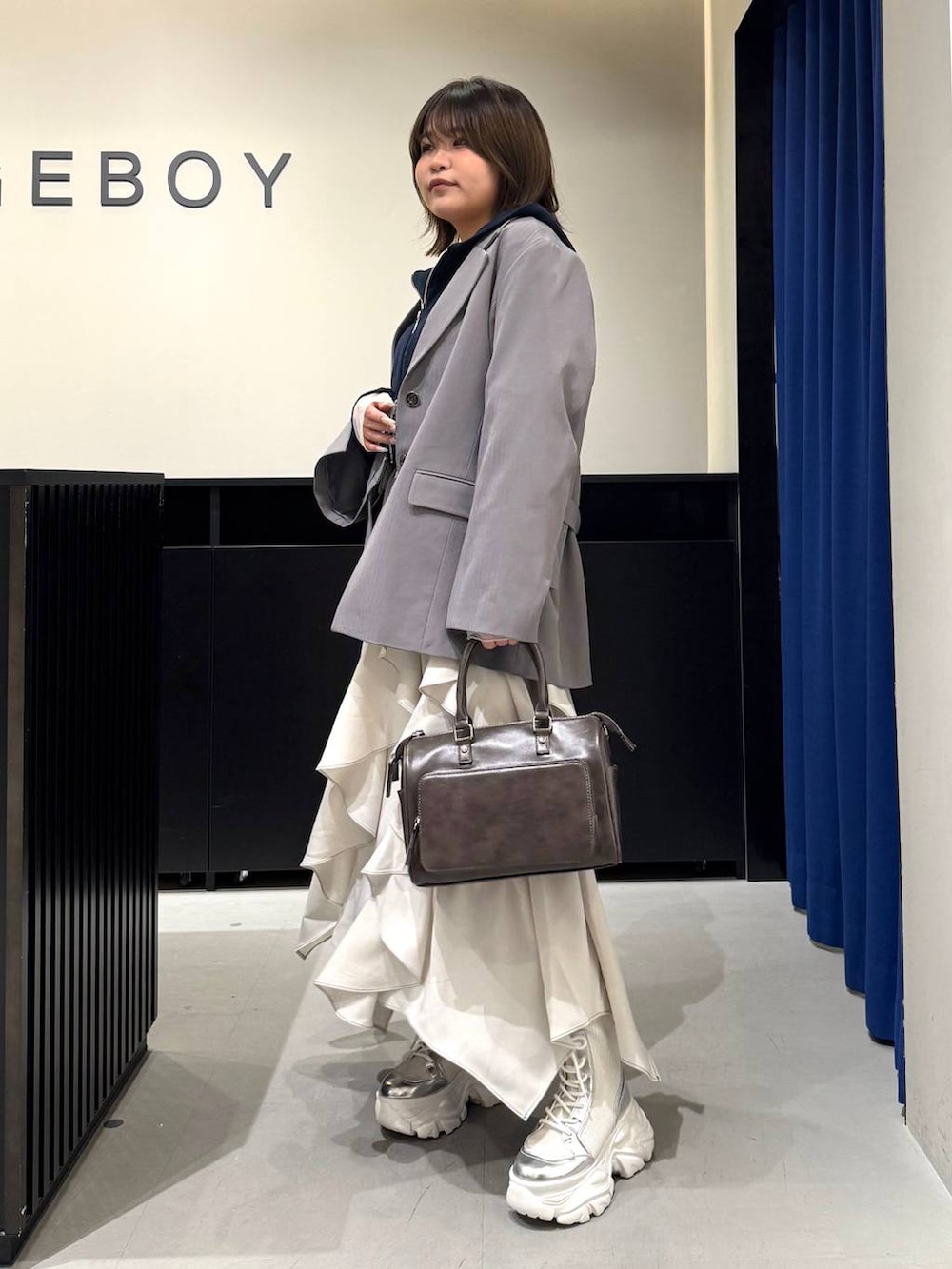 ホワイト系のブーツ、グレー系のテーラードジャケット、ベージュ系のスカートを着用したレディースの冬コーディネートの7枚目の写真