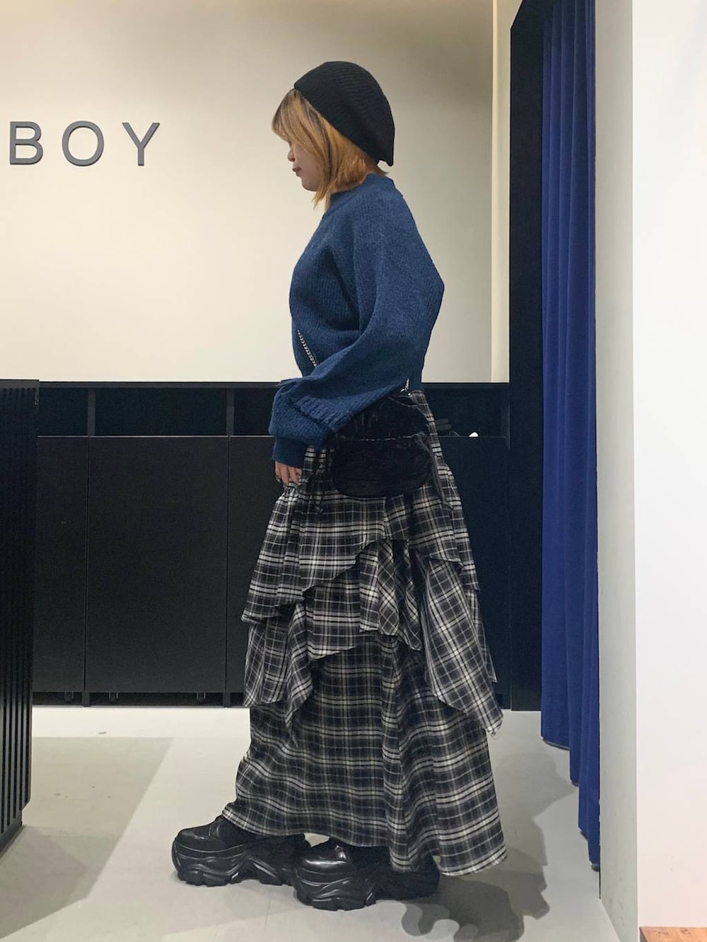 ブラック系のブーツ、ブラック系のスカート、ブラック系のハンドバッグを着用したレディースの冬コーディネートの6枚目の写真