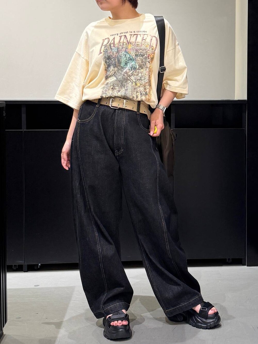 ブラック系のサンダル、ベージュ系のTシャツ/カットソー、ブラック系のデニムパンツを着用したレディースの夏コーディネートの2枚目の写真