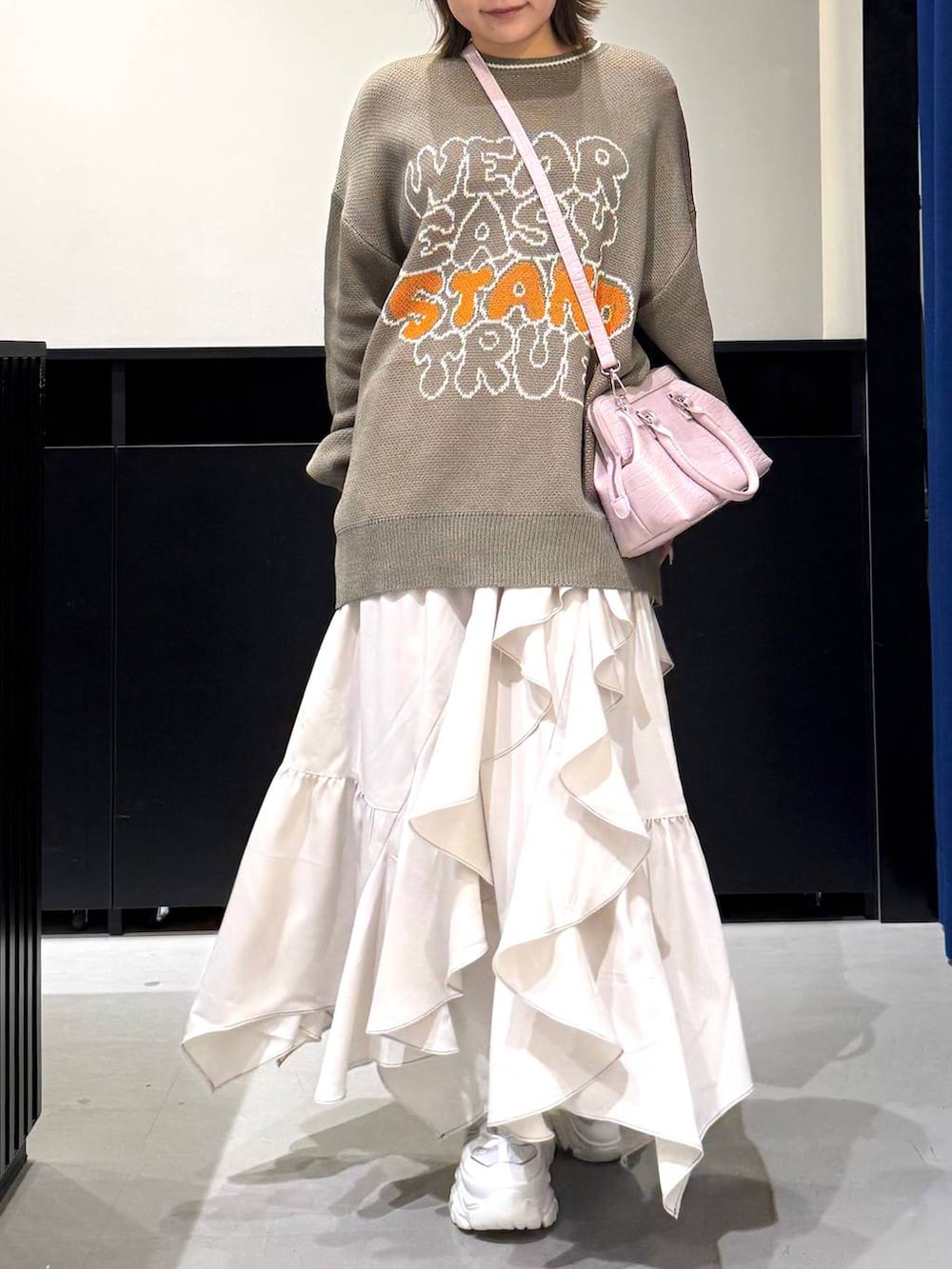 ホワイト系のスニーカー、ベージュ系のスカート、ピンク系のハンドバッグを着用したレディースの冬コーディネートの2枚目の写真