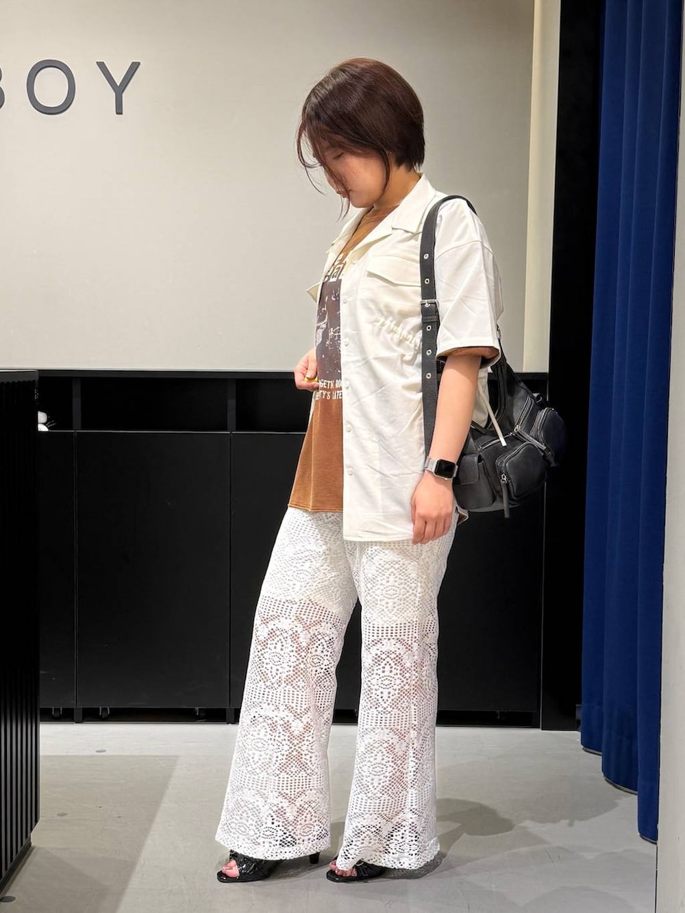 ブラック系のショルダーバッグ、ブラック系のサンダル、ホワイト系のTシャツ/カットソーを着用したレディースの夏コーディネートの3枚目の写真