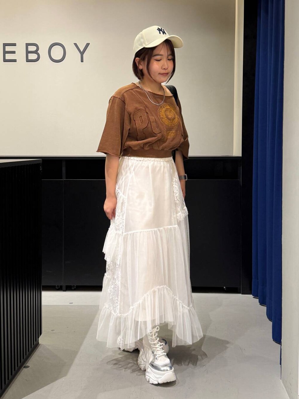 ホワイト系のブーツ、ブラウン系のTシャツ/カットソー、ブラック系のショルダーバッグを着用したレディースの夏コーディネートの3枚目の写真