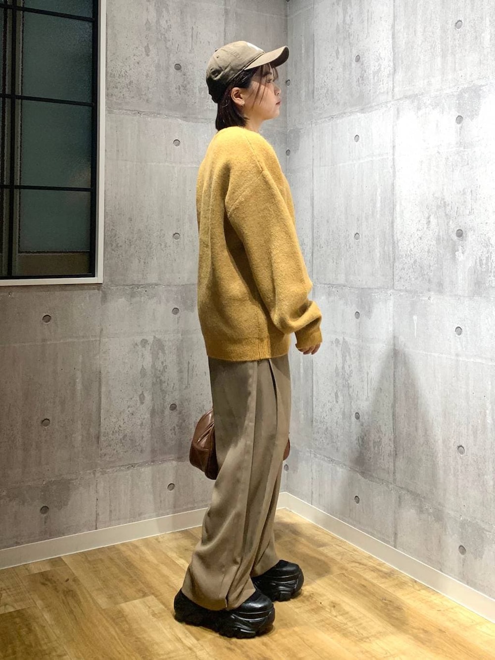 ブラック系のブーツ、イエロー系のボストンバッグ、イエロー系のニット/セーターを着用したレディースの秋コーディネートの3枚目の写真