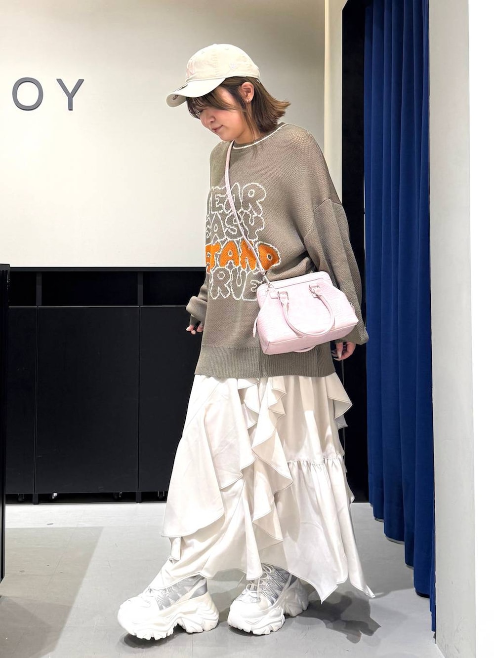 ホワイト系のスニーカー、ベージュ系のスカート、ピンク系のハンドバッグを着用したレディースの冬コーディネートの7枚目の写真