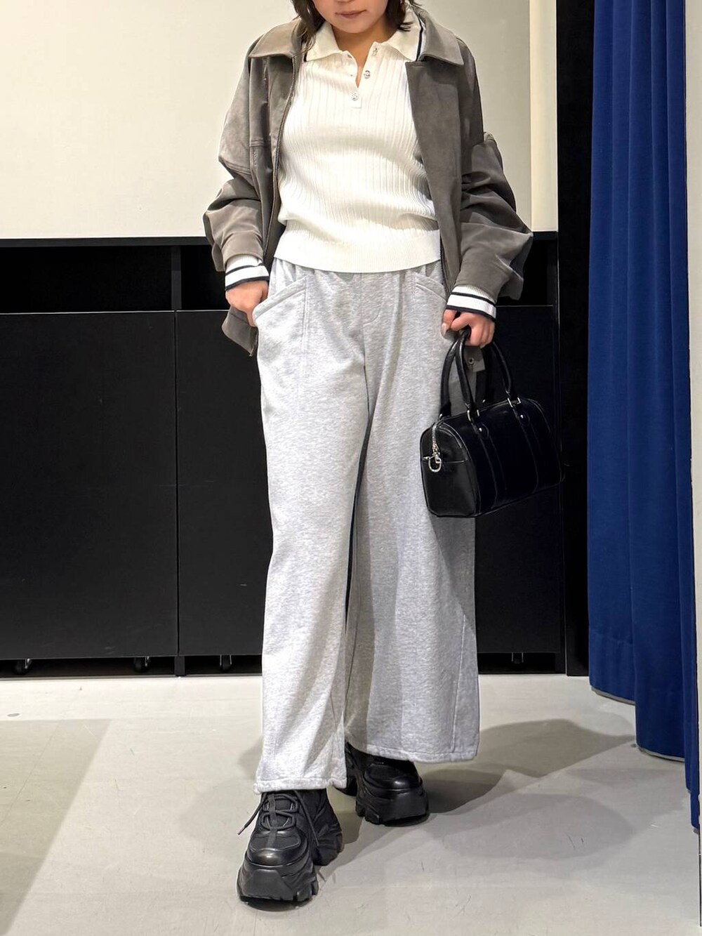 ブラック系のスニーカー、ブラック系のボストンバッグ、ホワイト系のニット/セーターを着用したレディースの冬コーディネートの2枚目の写真