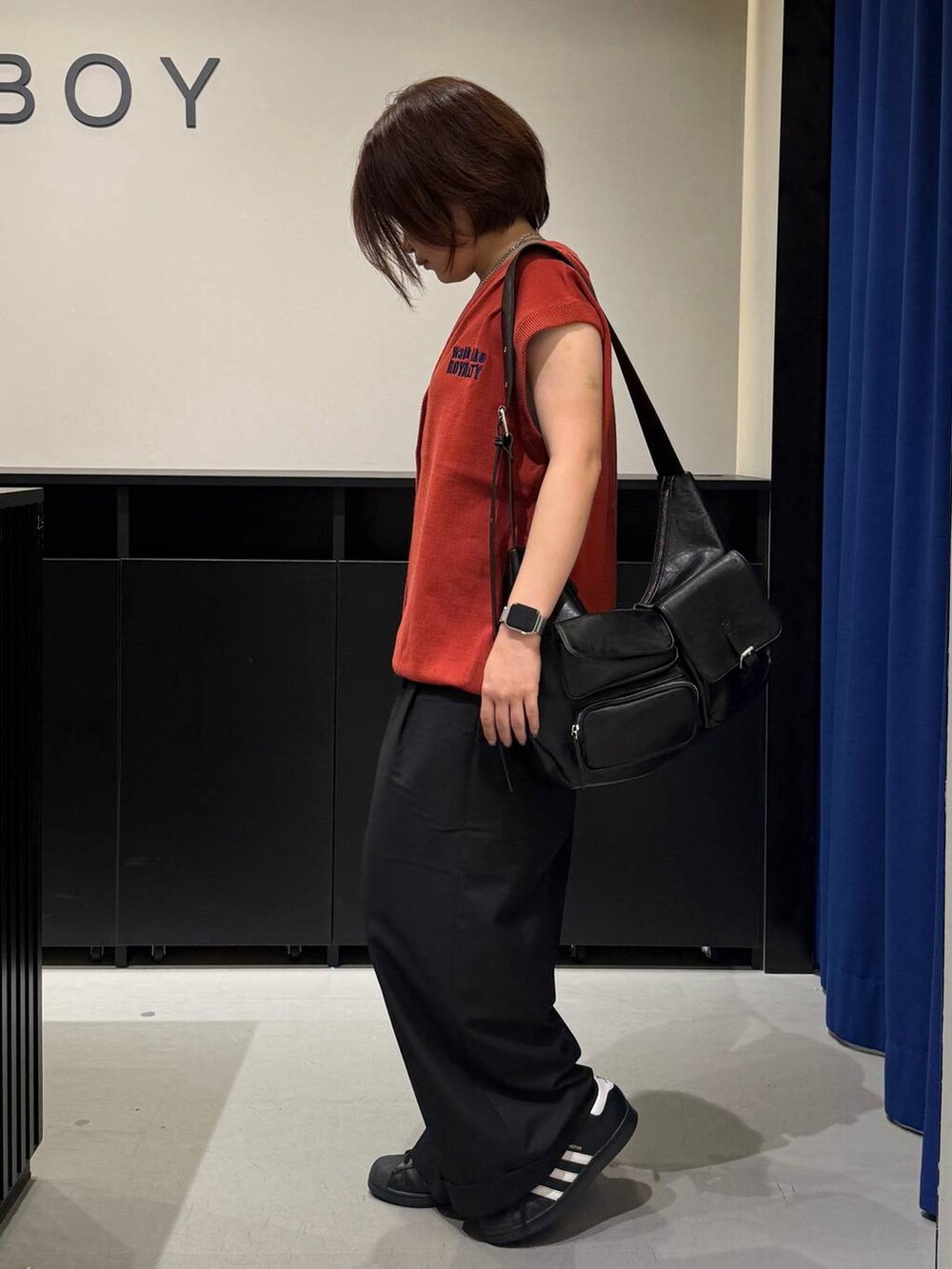 ホワイト系のキャミソール、ブラック系のスラックス、オレンジ系のベストを着用したレディースの夏コーディネートの6枚目の写真