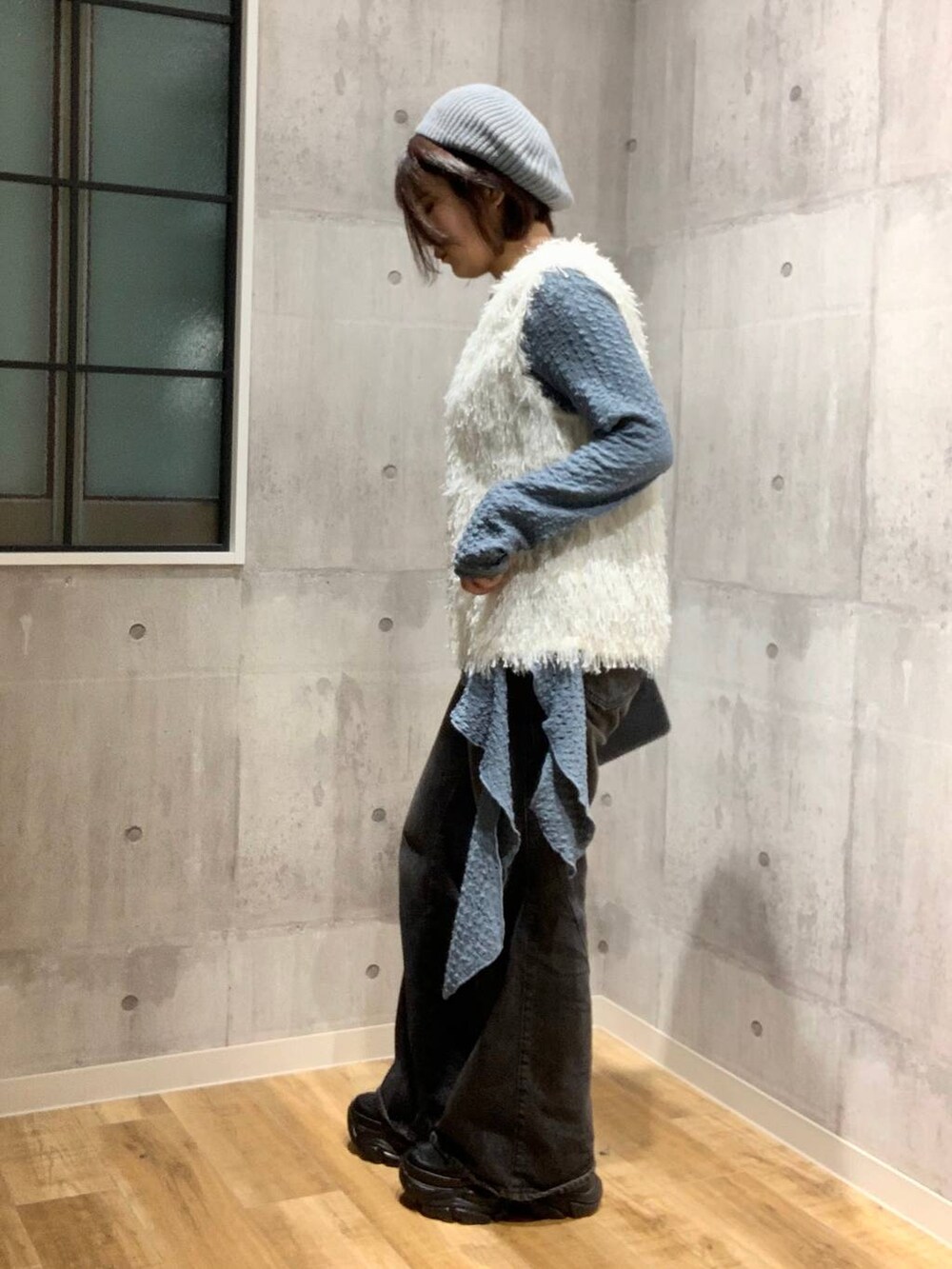 ブラック系のスニーカー、ブラック系のデニムパンツ、ホワイト系のベストを着用したレディースの秋コーディネートの6枚目の写真