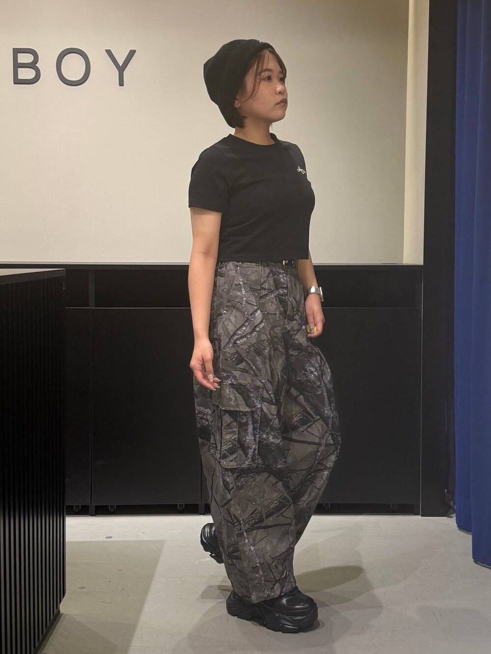 ブラック系のスニーカー、グレー系のカーゴパンツ、ブラック系のTシャツ/カットソーを着用したレディースの夏コーディネートの3枚目の写真