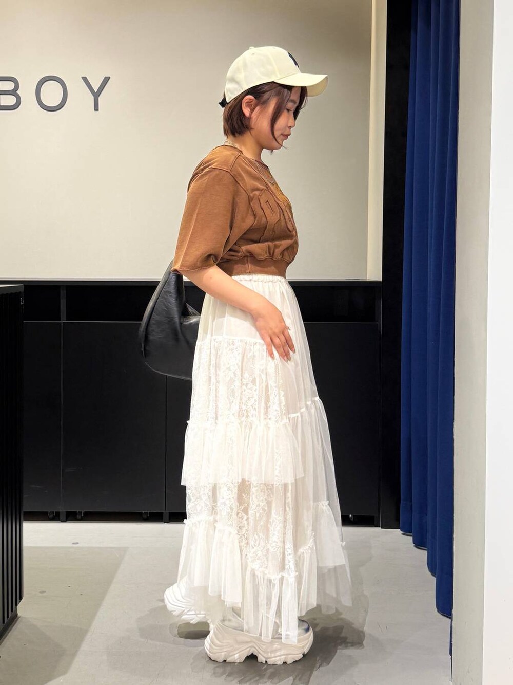 ホワイト系のブーツ、ブラウン系のTシャツ/カットソー、ブラック系のショルダーバッグを着用したレディースの夏コーディネートの4枚目の写真