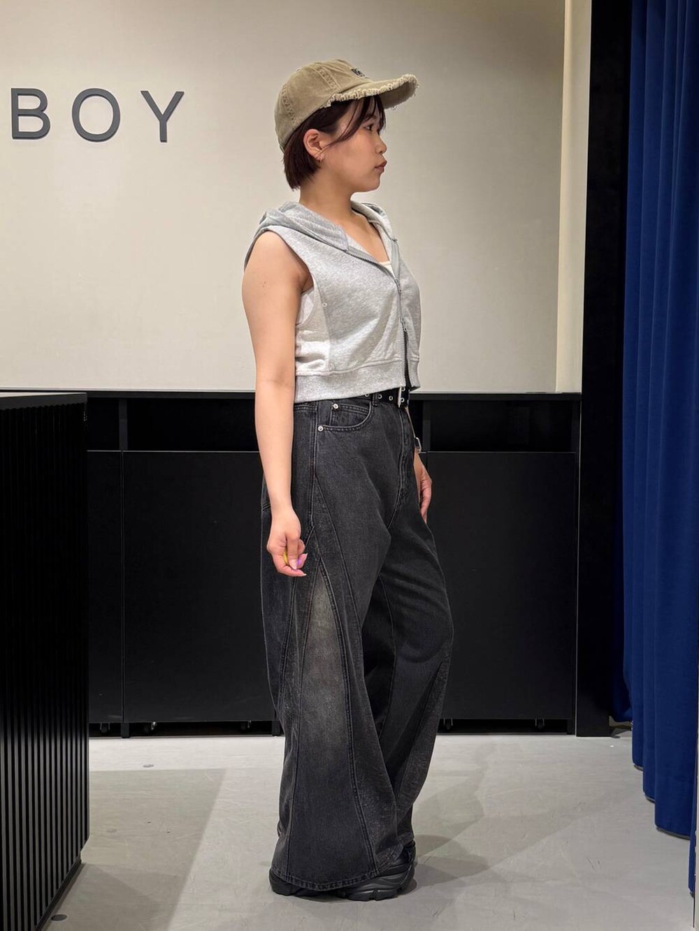 ブラック系のスニーカー、ホワイト系のキャミソール、ブラック系のデニムパンツを着用したレディースの夏コーディネートの4枚目の写真