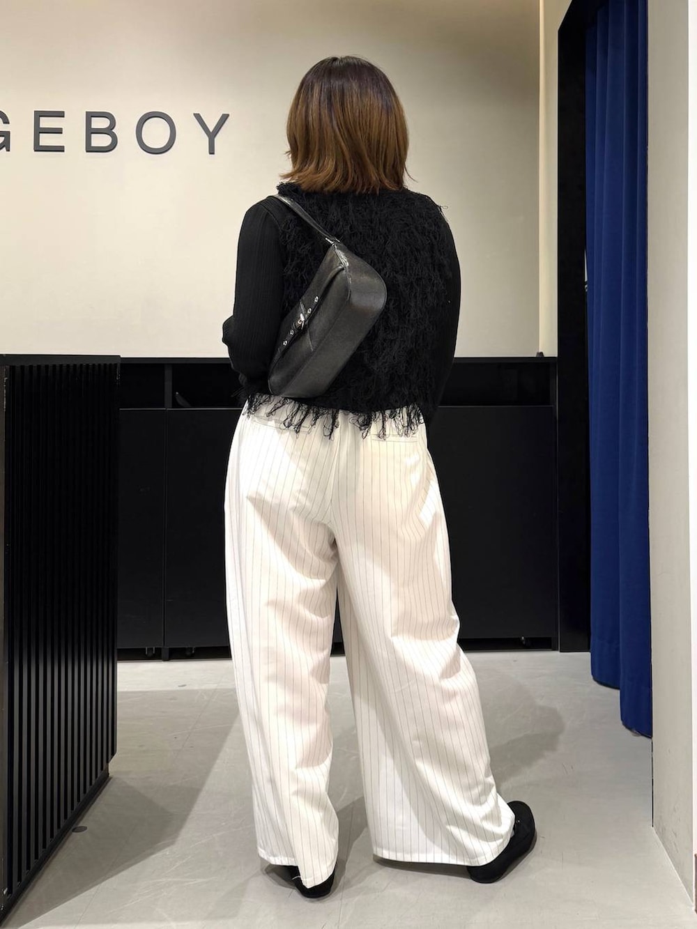 ブラック系のハンドバッグ、ブラック系のニット/セーター、ホワイト系のスラックスを着用したレディースの冬コーディネートの5枚目の写真