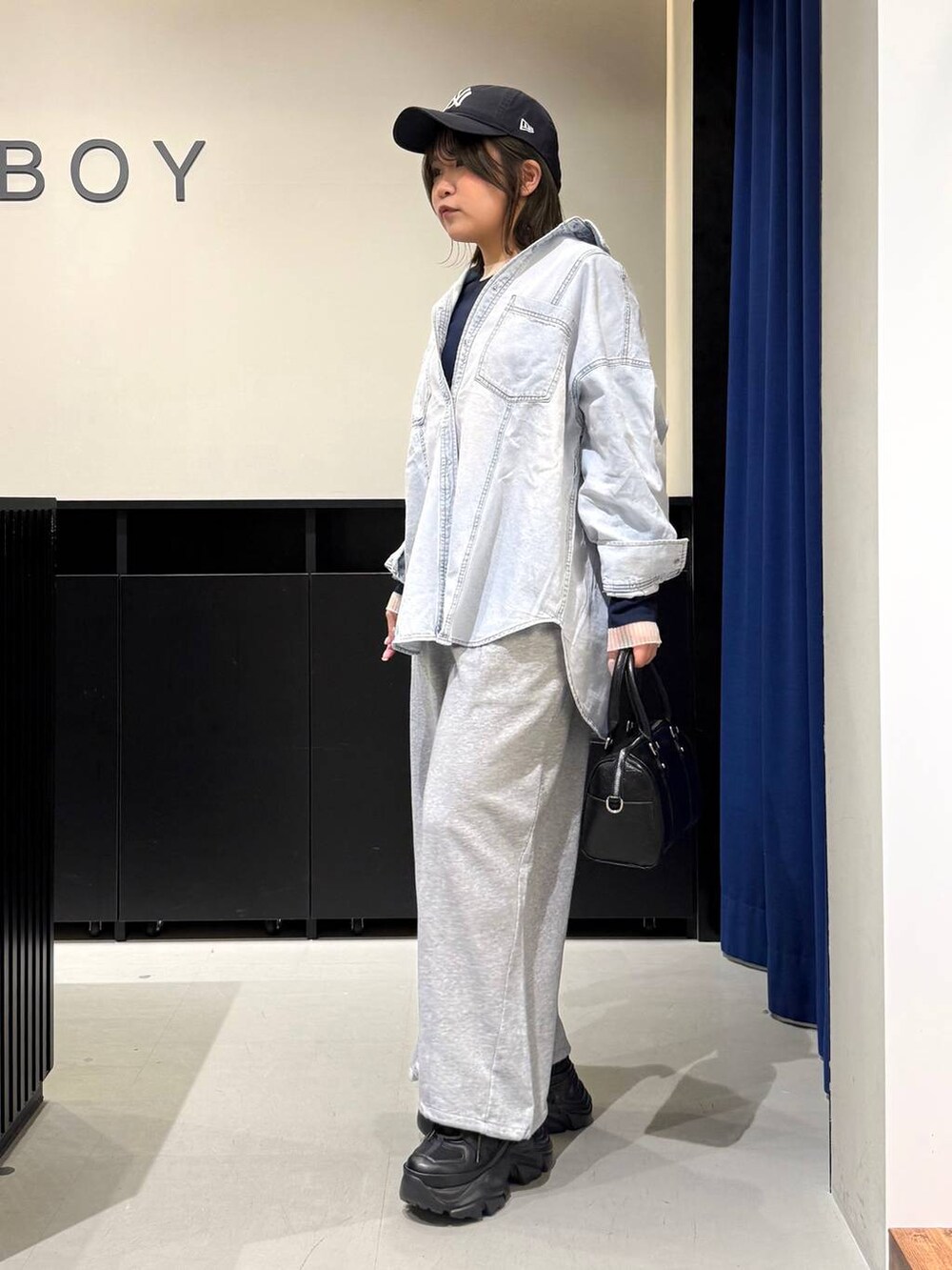 ブラック系のスニーカー、ブラック系のボストンバッグ、ブルー系のシャツ/ブラウスを着用したレディースの冬コーディネートの7枚目の写真