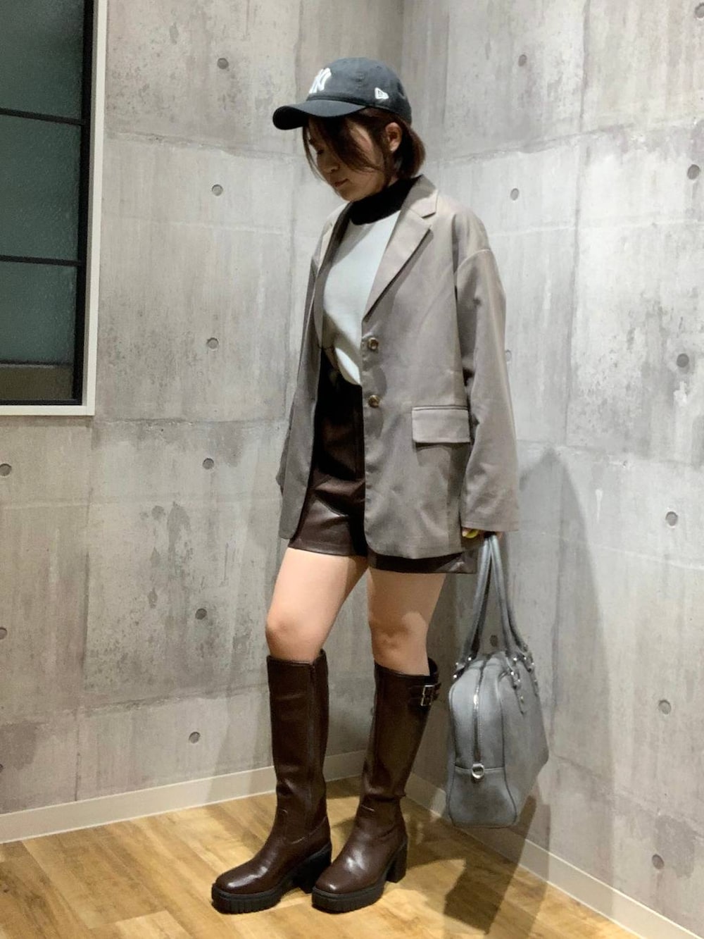 グレー系のボストンバッグ、ブラウン系のテーラードジャケット、ホワイト系のニット/セーターを着用したレディースの秋コーディネートの6枚目の写真