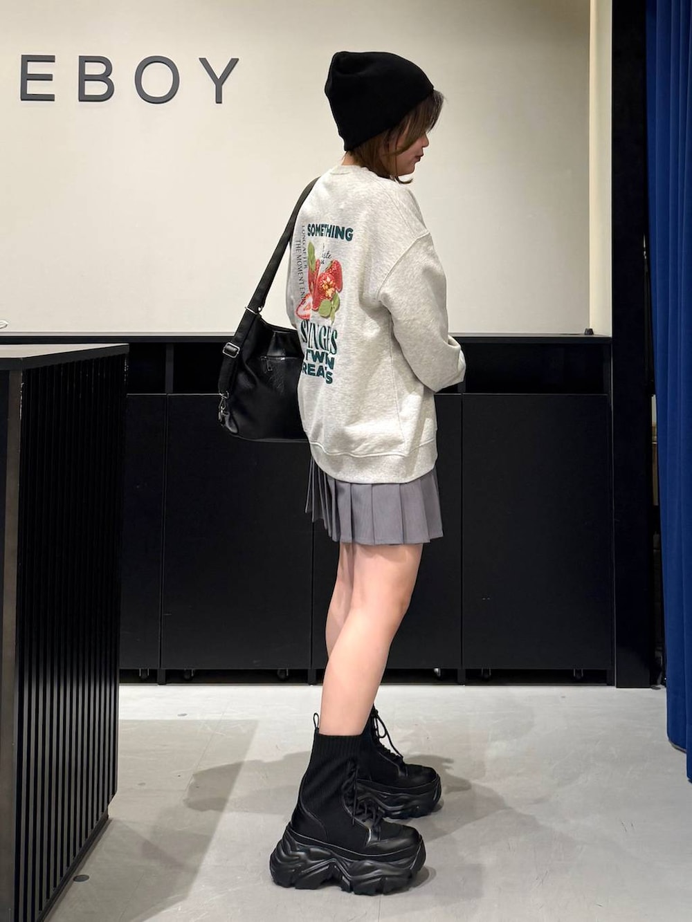 ブラック系のブーツ、グレー系のスウェット、ブラック系のショルダーバッグを着用したレディースの冬コーディネートの4枚目の写真