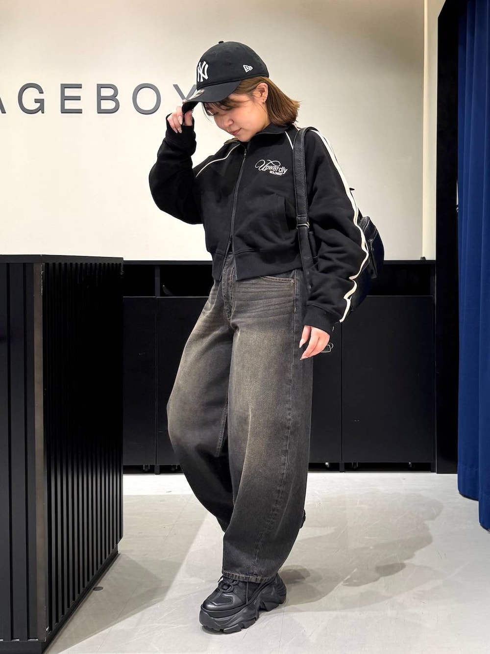 ブラック系のスニーカー、ブラック系のデニムパンツ、ブラック系のショルダーバッグを着用したレディースの冬コーディネートの7枚目の写真