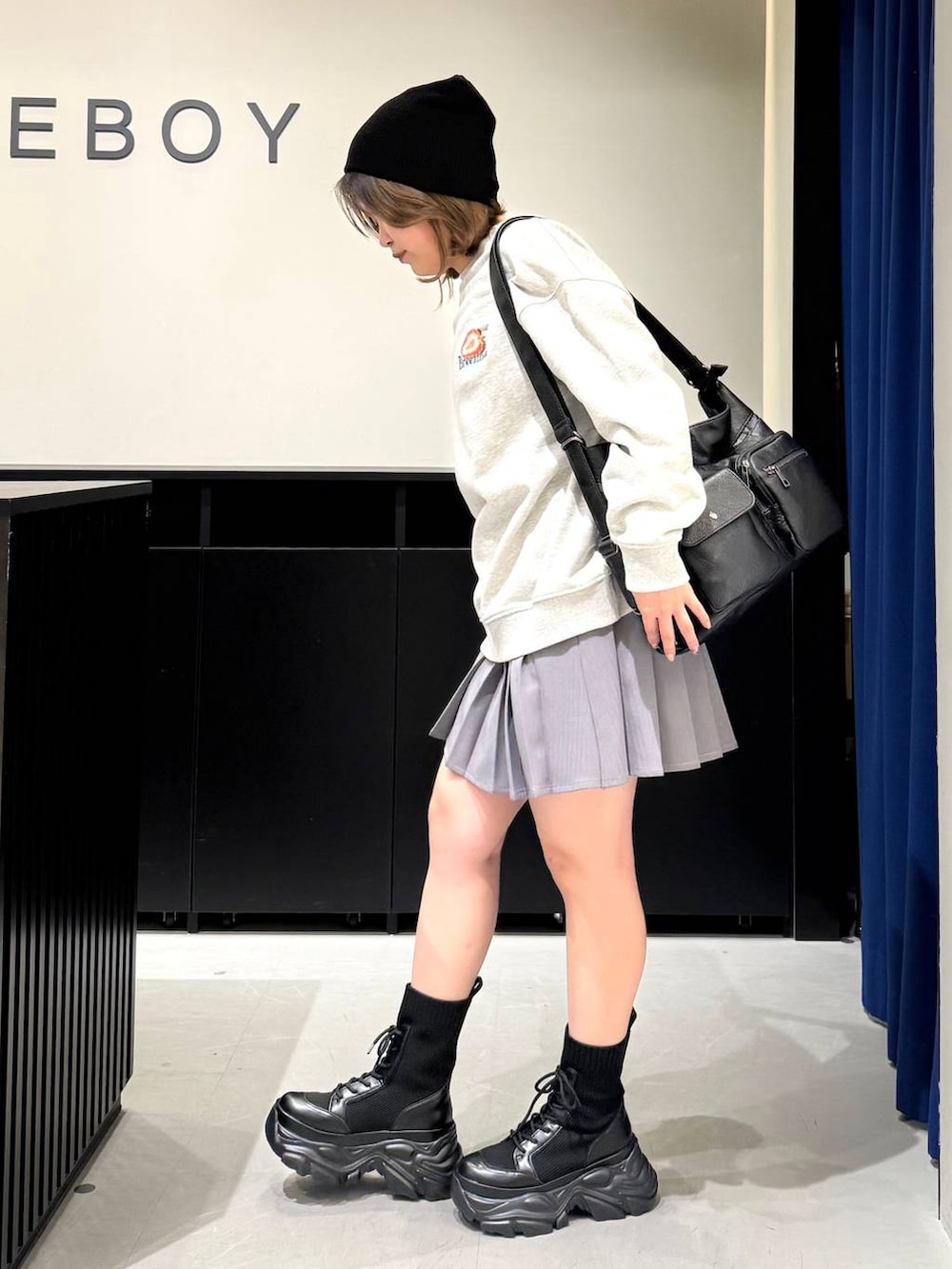 ブラック系のブーツ、グレー系のスウェット、ブラック系のショルダーバッグを着用したレディースの冬コーディネートの6枚目の写真