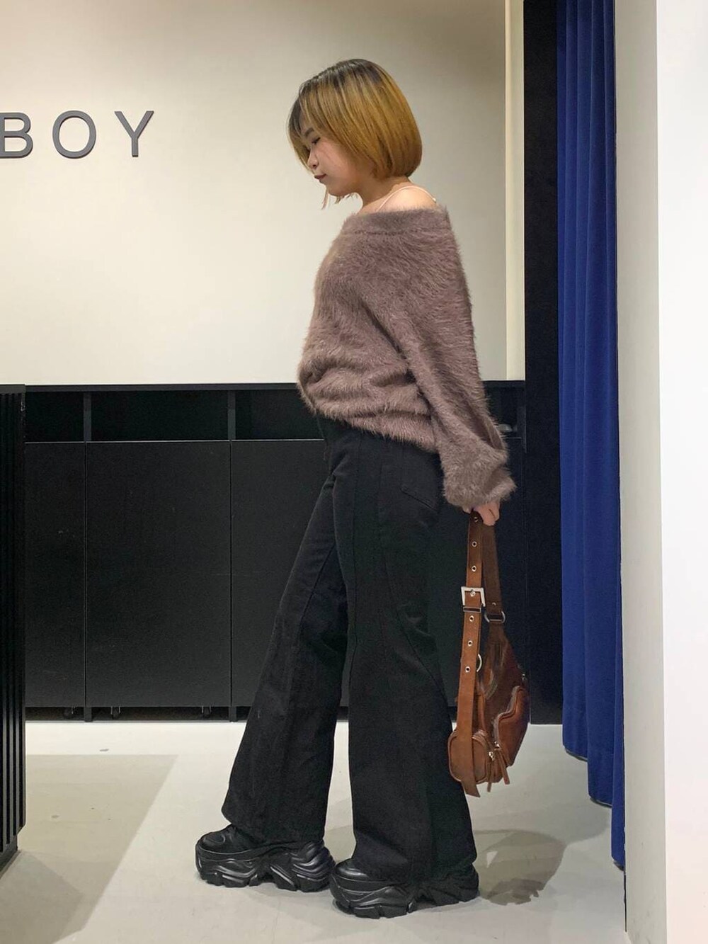 ブラック系のスニーカー、ブラック系のデニムパンツ、ブラウン系のニット/セーターを着用したレディースの冬コーディネートの6枚目の写真