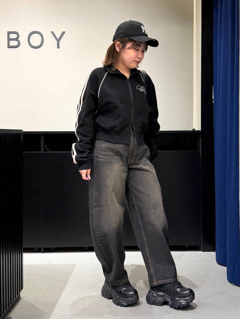 ブラック系のスニーカー、ブラック系のデニムパンツ、ブラック系のショルダーバッグを着用したレディースの冬コーディネートの3枚目の写真