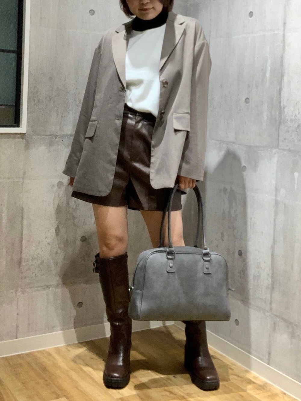 グレー系のボストンバッグ、ブラウン系のテーラードジャケット、ホワイト系のニット/セーターを着用したレディースの秋コーディネートの2枚目の写真