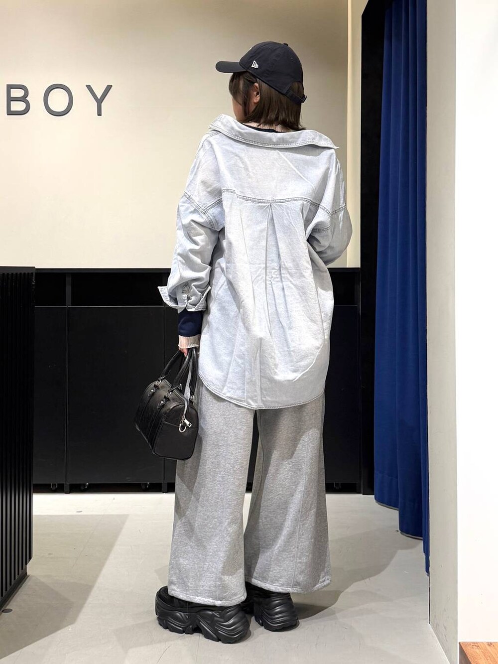 ブラック系のスニーカー、ブラック系のボストンバッグ、ブルー系のシャツ/ブラウスを着用したレディースの冬コーディネートの5枚目の写真