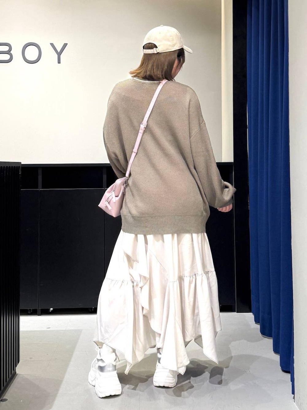 ホワイト系のスニーカー、ベージュ系のスカート、ピンク系のハンドバッグを着用したレディースの冬コーディネートの5枚目の写真