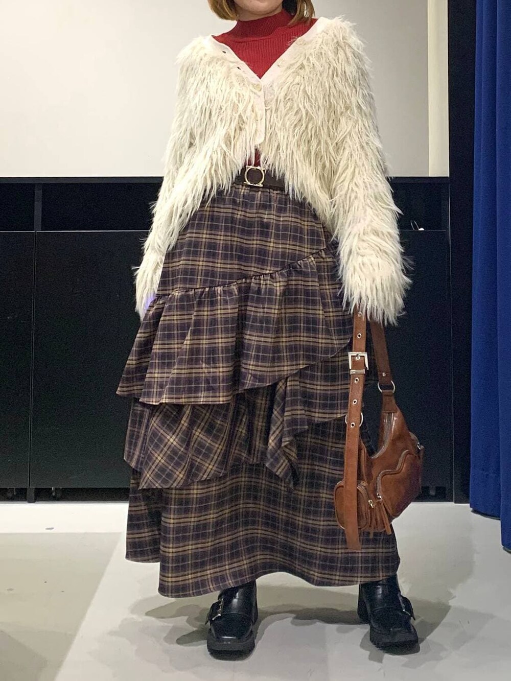 ブラック系のブーツ、ブラウン系のスカート、ブラウン系のショルダーバッグを着用したレディースの冬コーディネートの2枚目の写真