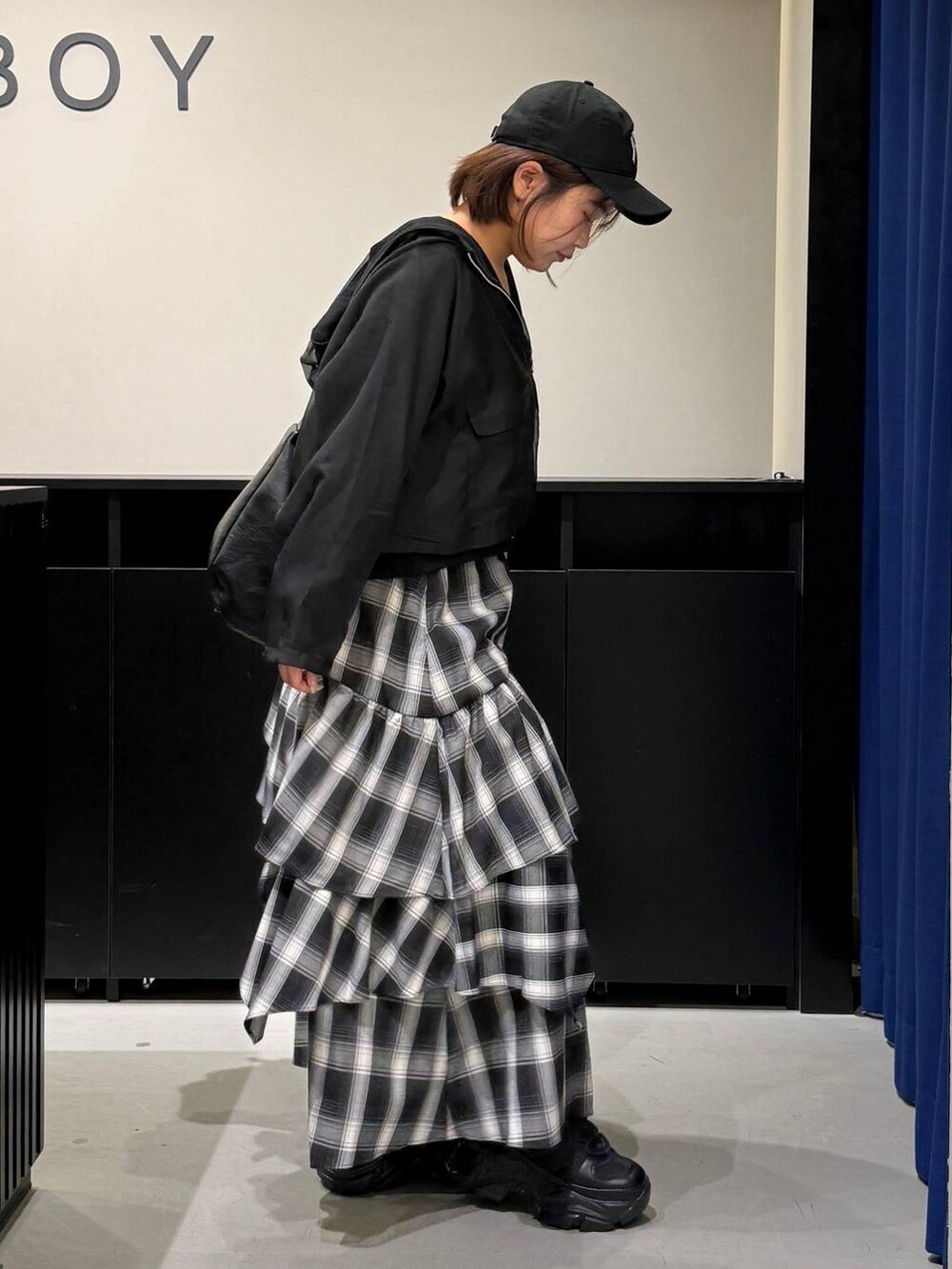 ブラック系のスニーカー、ブラック系のショルダーバッグ、ホワイト系のスカートを着用したレディースの秋コーディネートの4枚目の写真