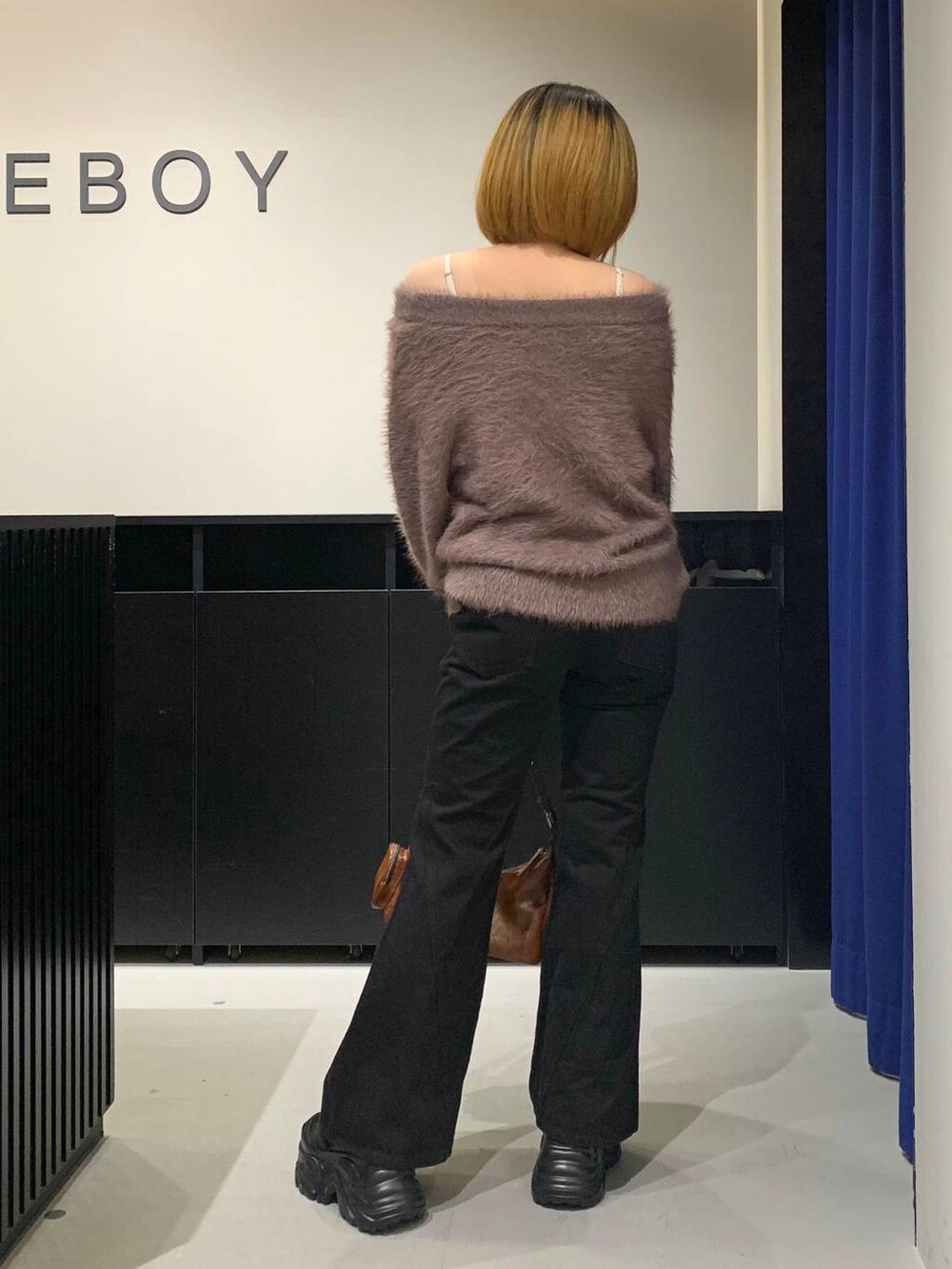 ブラック系のスニーカー、ブラック系のデニムパンツ、ブラウン系のニット/セーターを着用したレディースの冬コーディネートの5枚目の写真