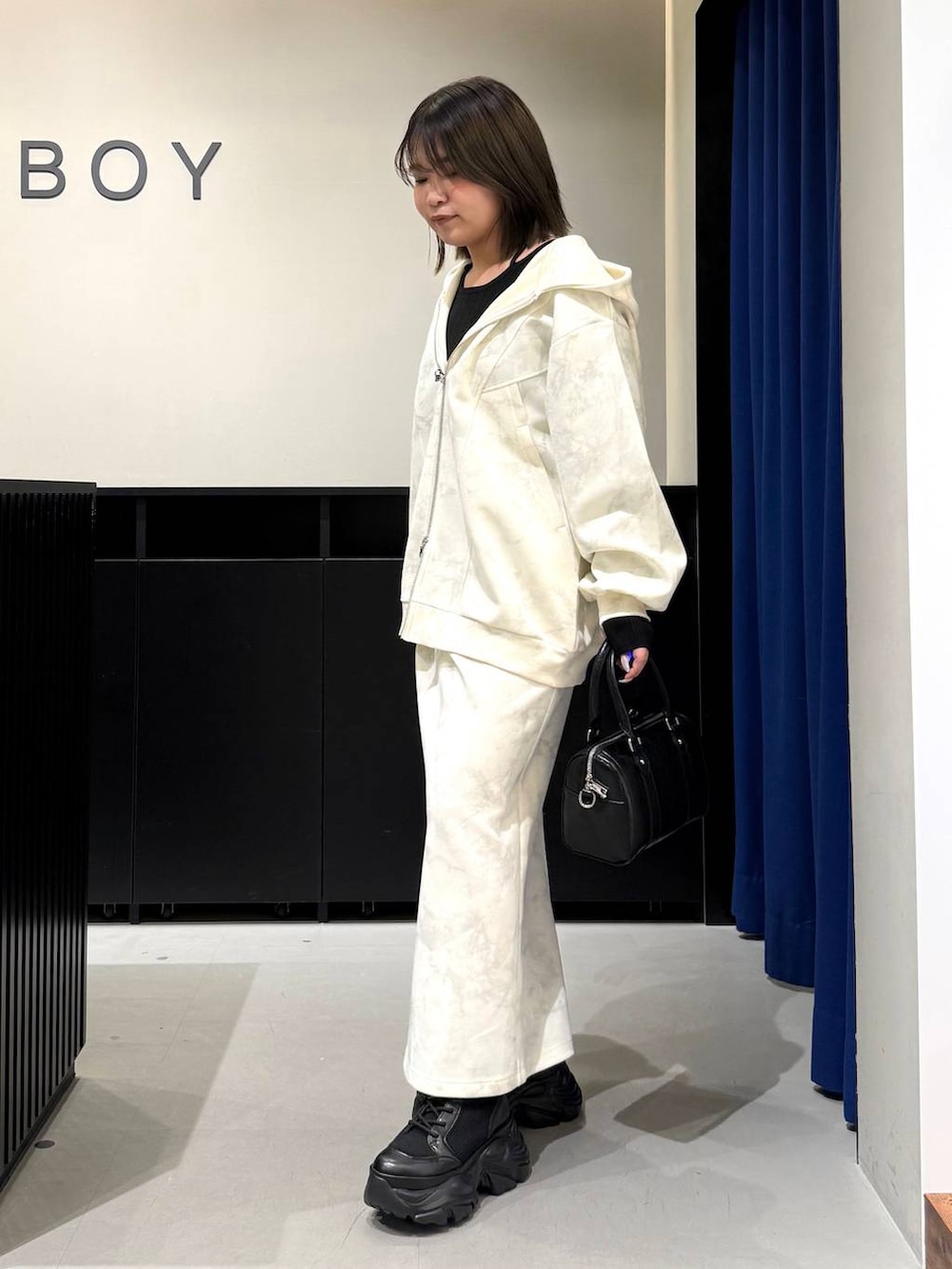 ブラック系のブーツ、ホワイト系のスカート、ホワイト系のパーカーを着用したレディースの冬コーディネートの7枚目の写真