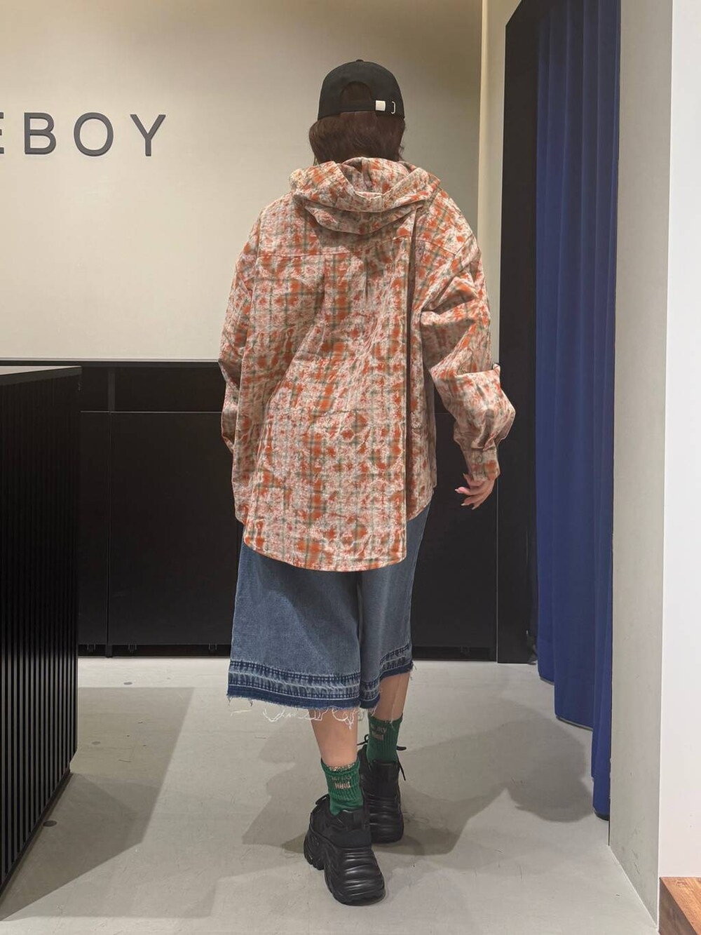 ブラック系のスニーカー、ブルー系のデニムパンツ、オレンジ系のシャツ/ブラウスを着用したレディースの夏コーディネートの5枚目の写真