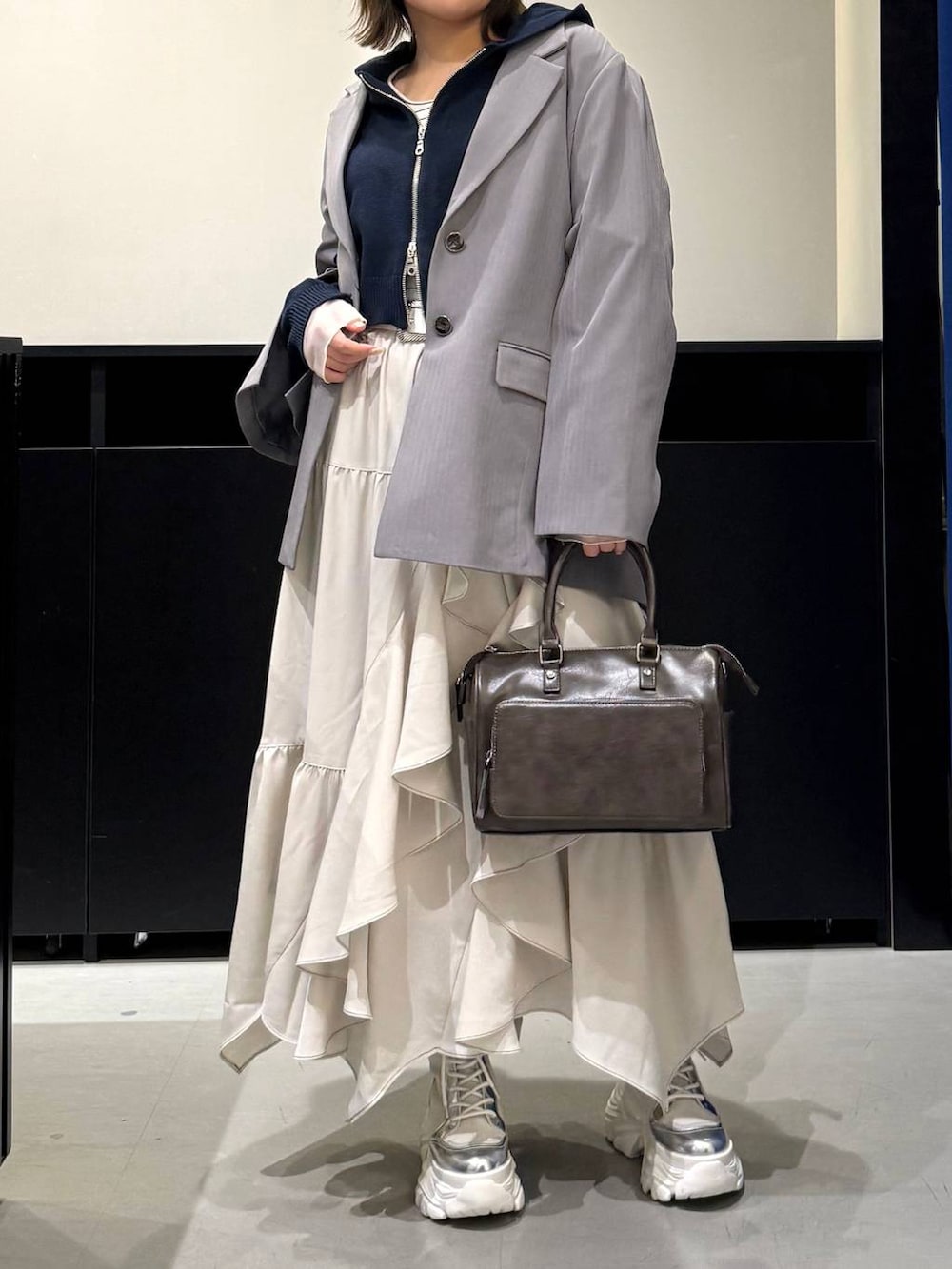 ホワイト系のブーツ、グレー系のテーラードジャケット、ベージュ系のスカートを着用したレディースの冬コーディネートの2枚目の写真