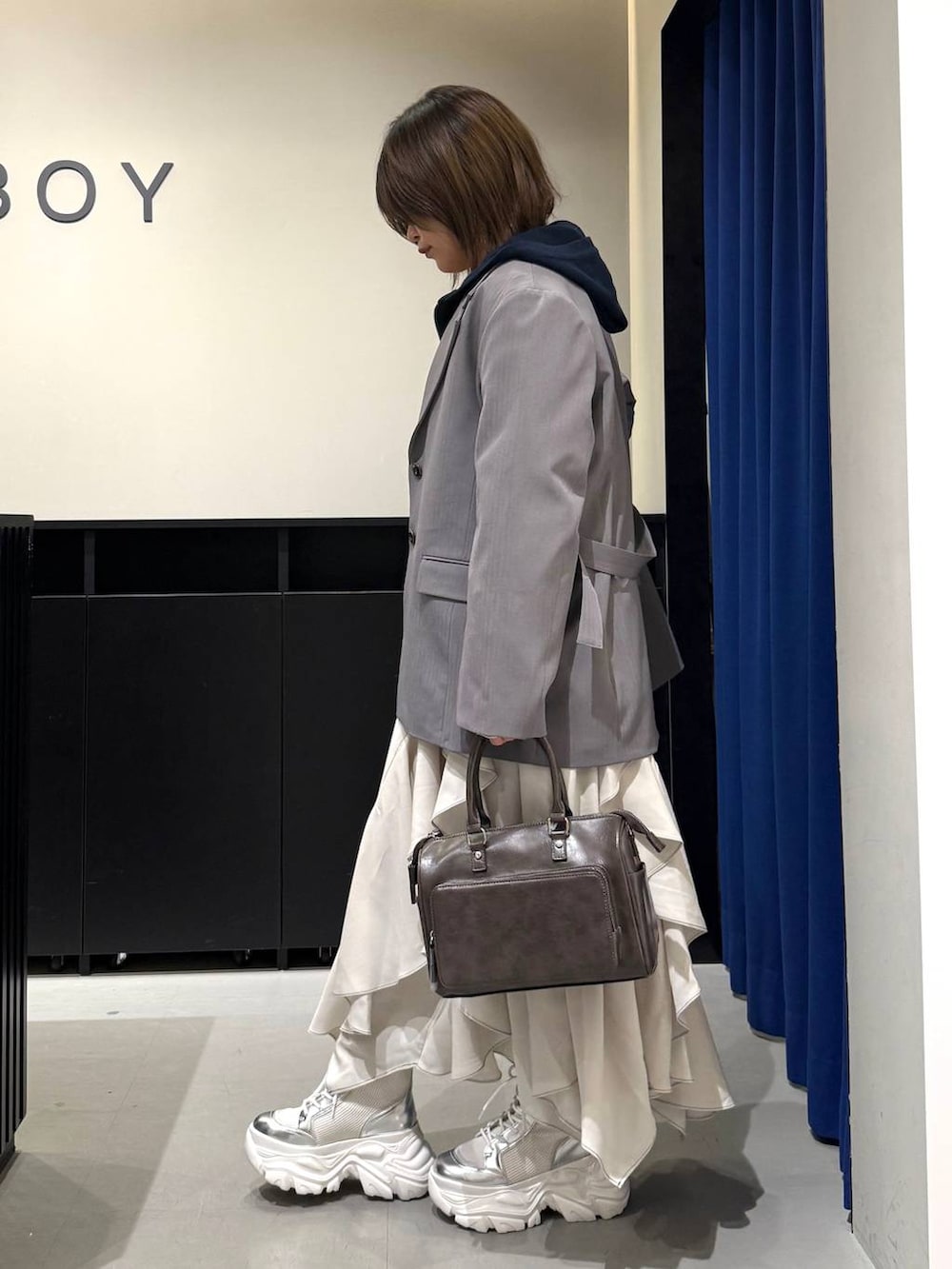 ホワイト系のブーツ、グレー系のテーラードジャケット、ベージュ系のスカートを着用したレディースの冬コーディネートの6枚目の写真