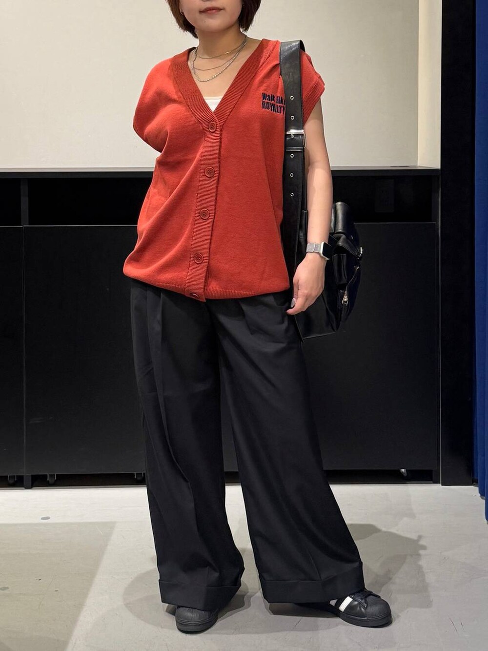 ホワイト系のキャミソール、ブラック系のスラックス、オレンジ系のベストを着用したレディースの夏コーディネートの2枚目の写真