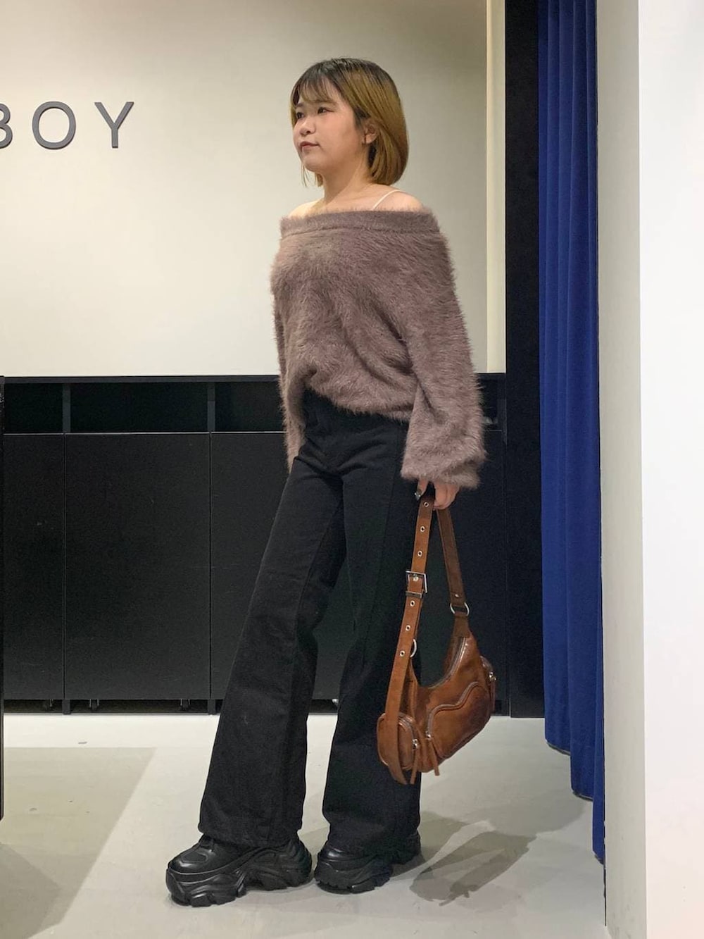 ブラック系のスニーカー、ブラック系のデニムパンツ、ブラウン系のニット/セーターを着用したレディースの冬コーディネートの7枚目の写真