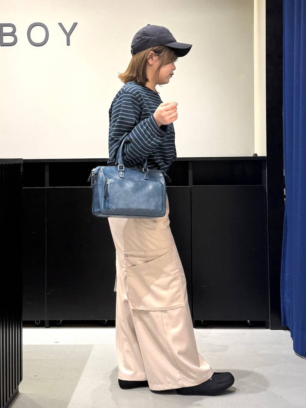 ホワイト系のキャミソール、ブルー系のショルダーバッグ、ベージュ系のスラックスを着用したレディースの冬コーディネートの3枚目の写真