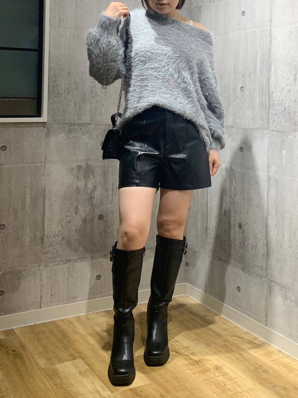 ブラック系のブーツ、ブラック系のハンドバッグ、グレー系のニット/セーターを着用したレディースの秋コーディネートの2枚目の写真