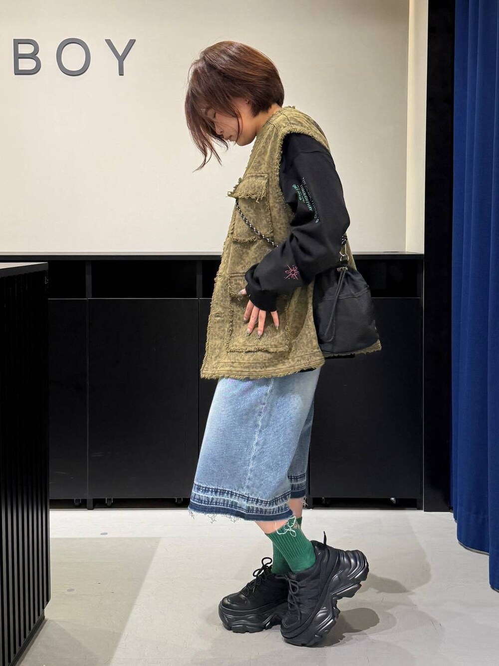 ブラック系のスニーカー、ブラック系のショルダーバッグ、ブルー系のデニムパンツを着用したレディースの夏コーディネートの7枚目の写真