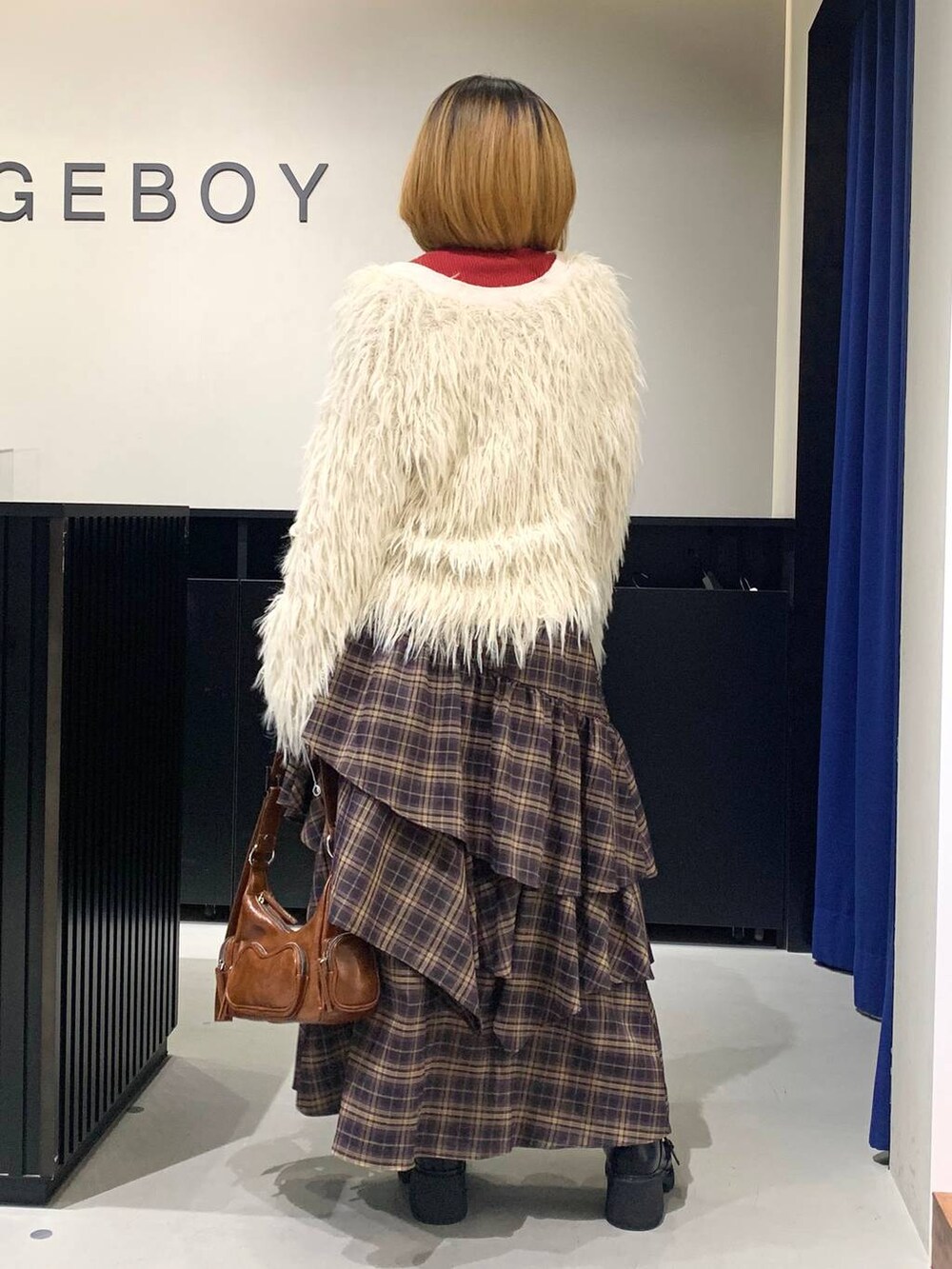 ブラック系のブーツ、ブラウン系のスカート、ブラウン系のショルダーバッグを着用したレディースの冬コーディネートの6枚目の写真