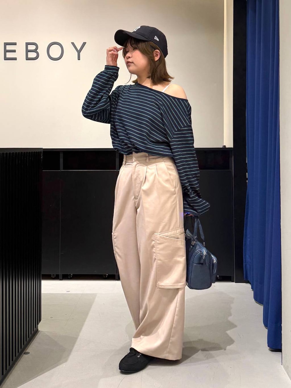 ホワイト系のキャミソール、ブルー系のショルダーバッグ、ベージュ系のスラックスを着用したレディースの冬コーディネートの6枚目の写真