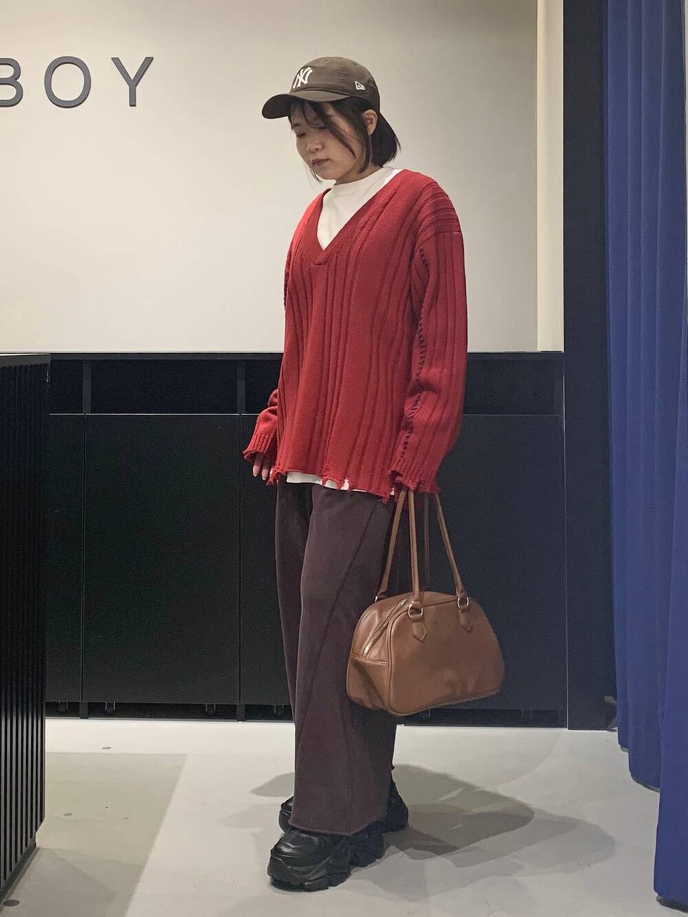 ブラック系のブーツ、ブラウン系のスウェットパンツ、イエロー系のボストンバッグを着用したレディースの秋コーディネートの7枚目の写真