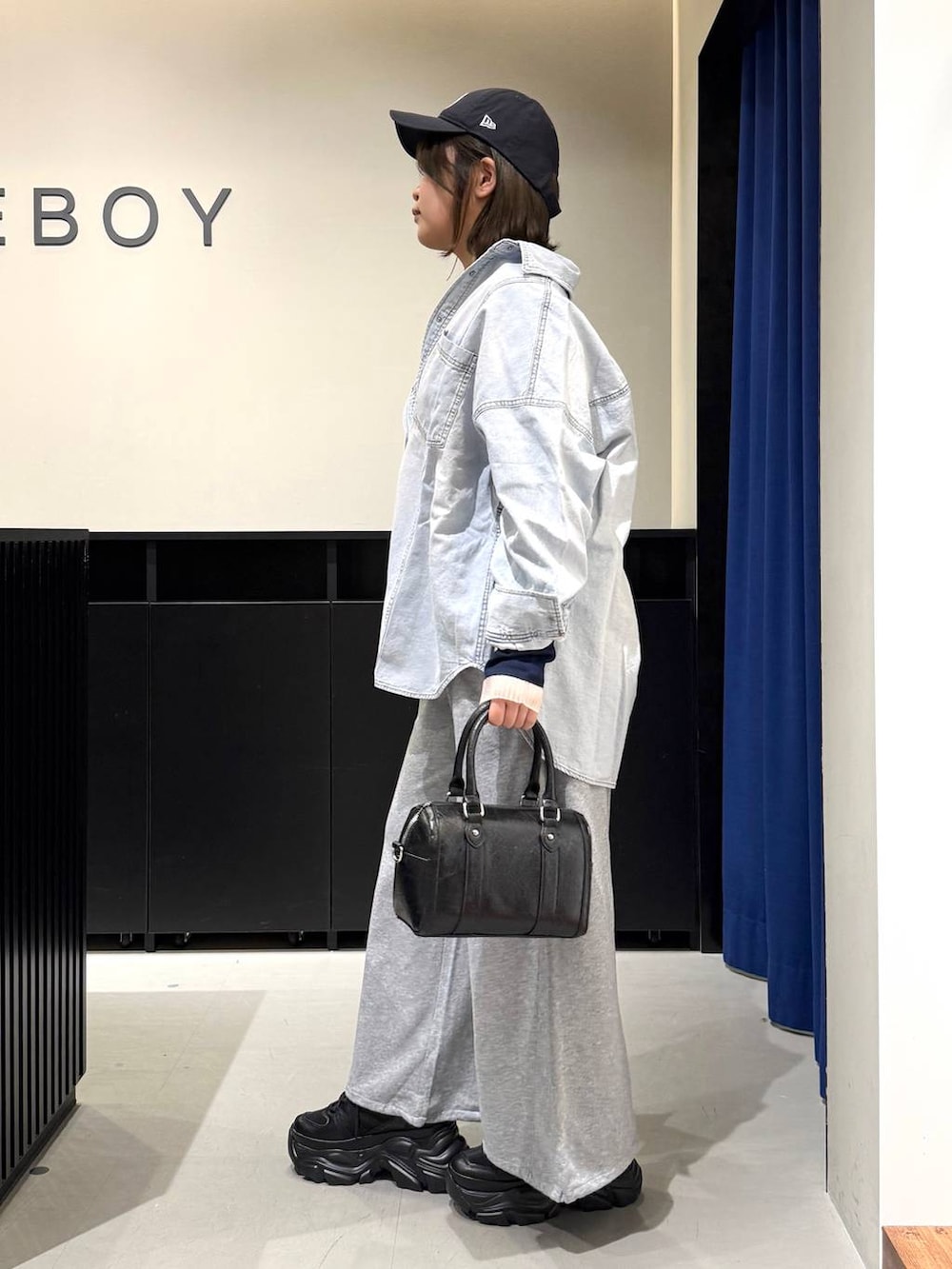 ブラック系のスニーカー、ブラック系のボストンバッグ、ブルー系のシャツ/ブラウスを着用したレディースの冬コーディネートの6枚目の写真