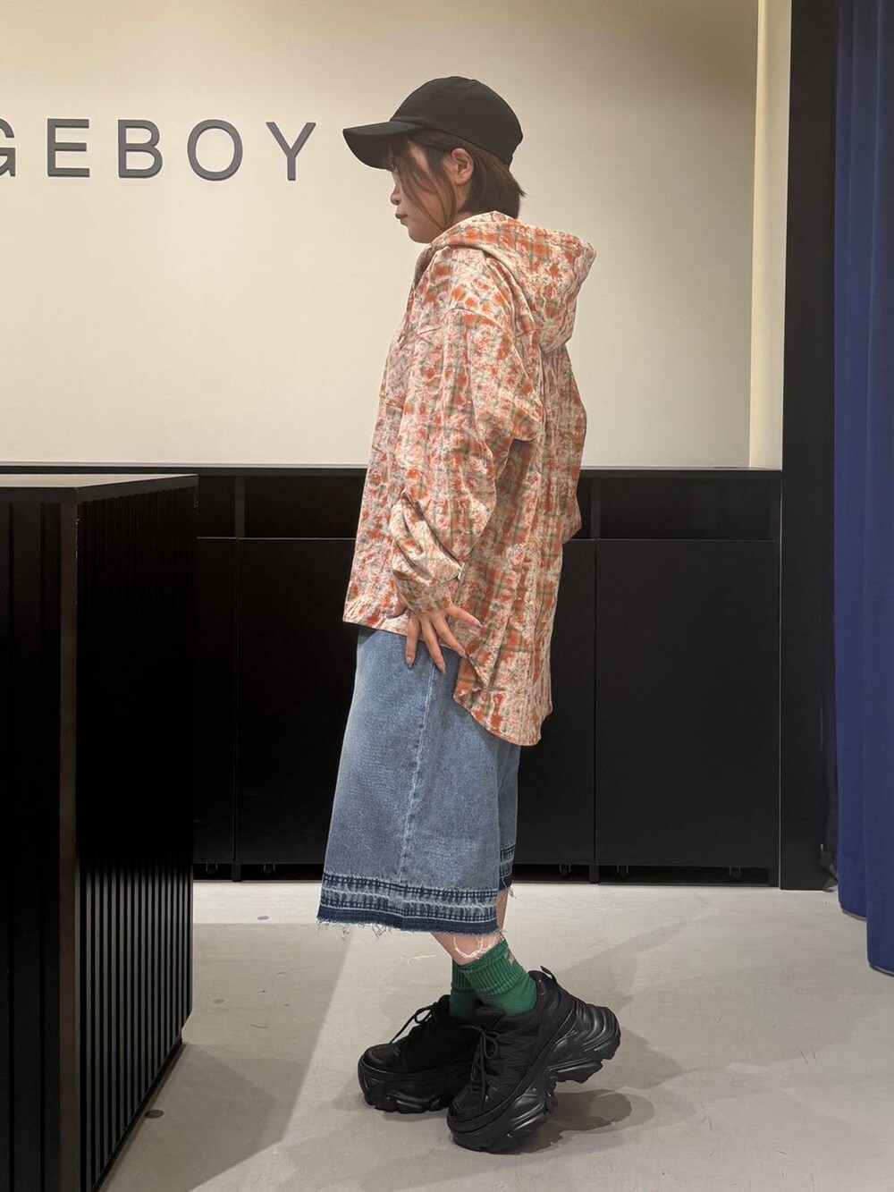 ブラック系のスニーカー、ブルー系のデニムパンツ、オレンジ系のシャツ/ブラウスを着用したレディースの夏コーディネートの6枚目の写真