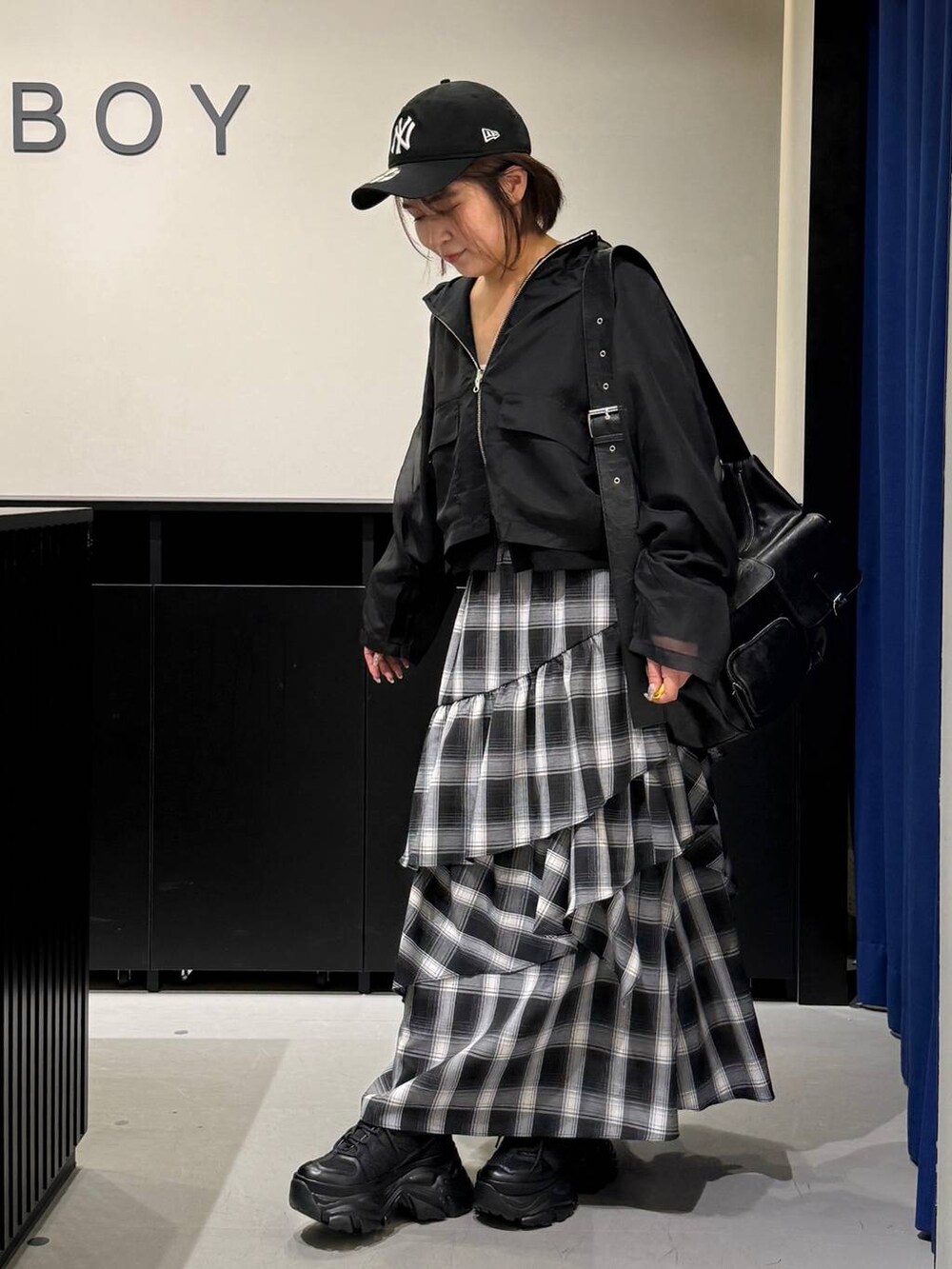 ブラック系のスニーカー、ブラック系のショルダーバッグ、ホワイト系のスカートを着用したレディースの秋コーディネートの7枚目の写真