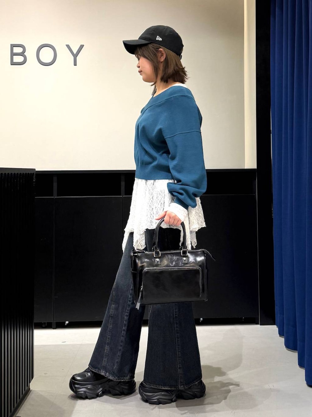 ブラック系のスニーカー、ブルー系のデニムパンツ、グリーン系のニット/セーターを着用したレディースの冬コーディネートの6枚目の写真