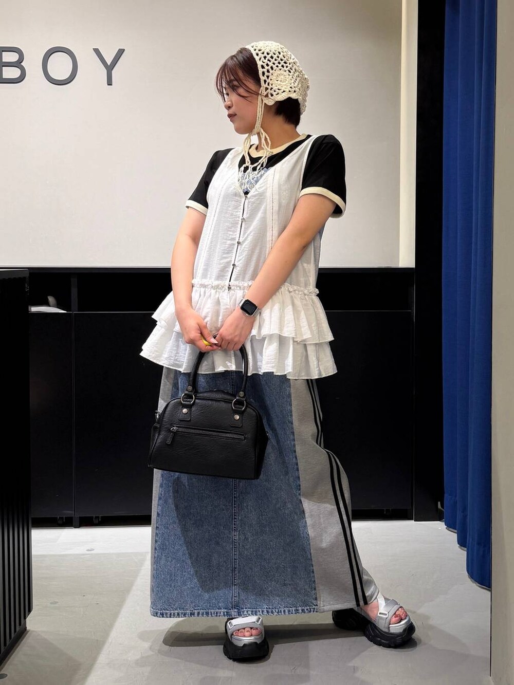 グレー系のサンダル、ブルー系のスカート、ブラック系のショルダーバッグを着用したレディースの夏コーディネートの2枚目の写真