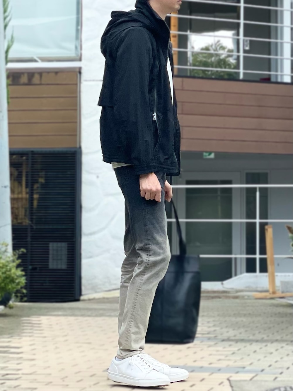 グレー系のブルゾン、ホワイト系のニット/セーター、ブラック系のデニムパンツを着用したメンズの秋コーディネートの2枚目の写真